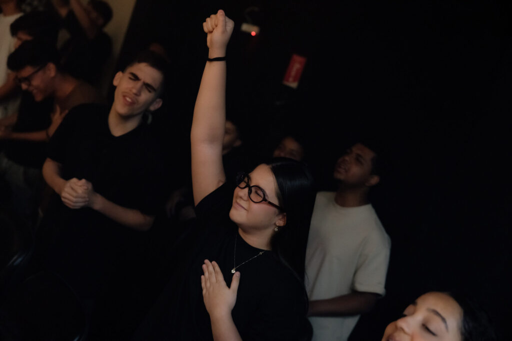 Participantes com as mãos levantadas durante um momento de adoração.