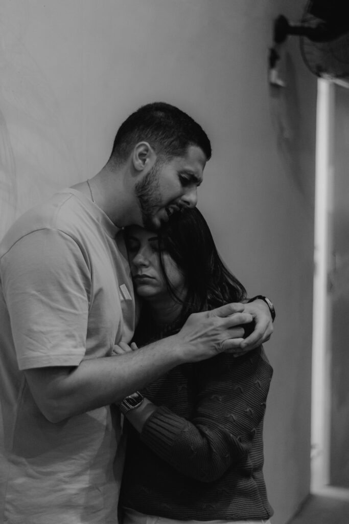 Homem abraça uma mulher durante um momento de acolhimento e oração.