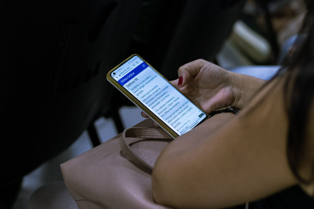 Pessoa lê o Salmo 90 em um aplicativo de Bíblia no celular durante encontro da igreja